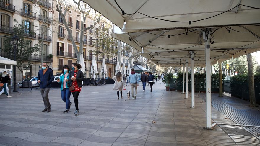 Varias personas pasan junto a las terrazas de Las Ramblas de Barcelona. EFE/ Toni Albir