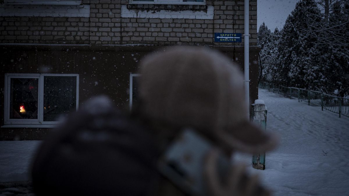 Una mujer camina frente a la señal del refugio donde se ha creado una escuela o centro para que los estudiantes reciban clases no regladas que compatibilicen con sus clases on line, ante la destrucción del colegio de la licalidad en un bombardeo de drones rusos.
