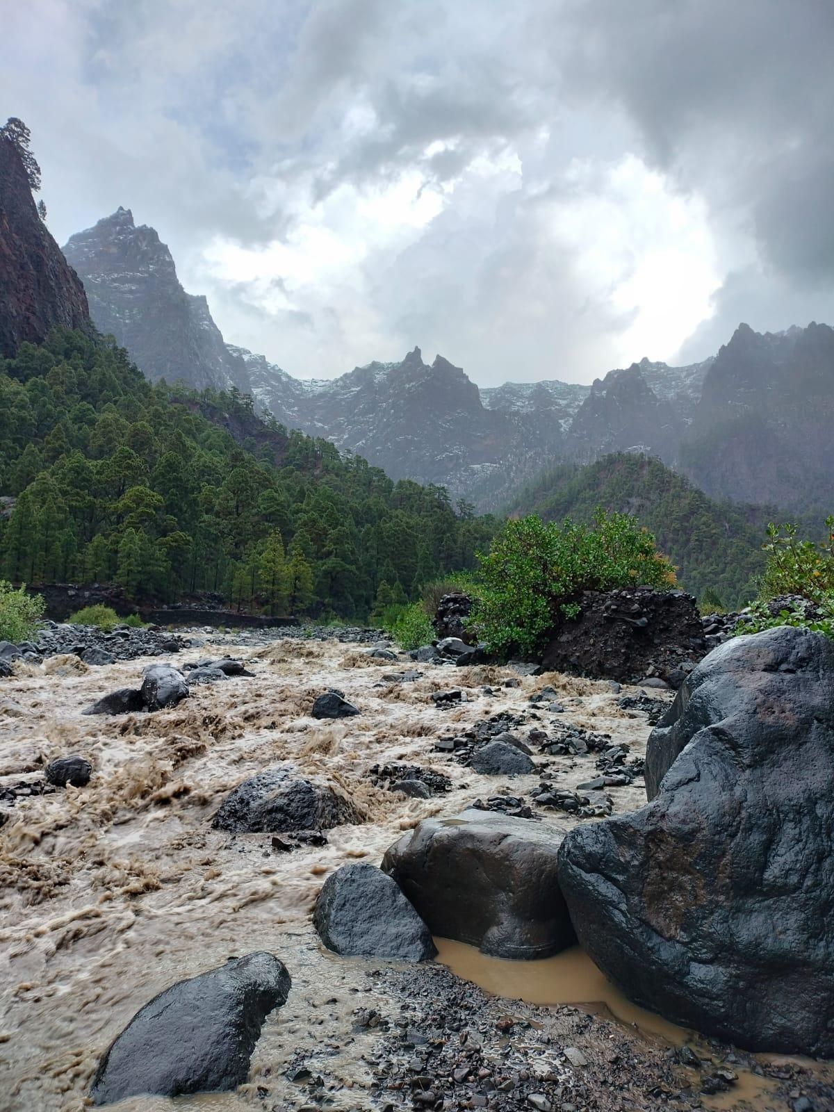 En la imagen, el Barranco de Taburiente, en el interior del Parque Nacional de La Caldera,   el martes, con el agua color chocolate por las lluvias de estos días, y las cumbres nevadas al fondo.