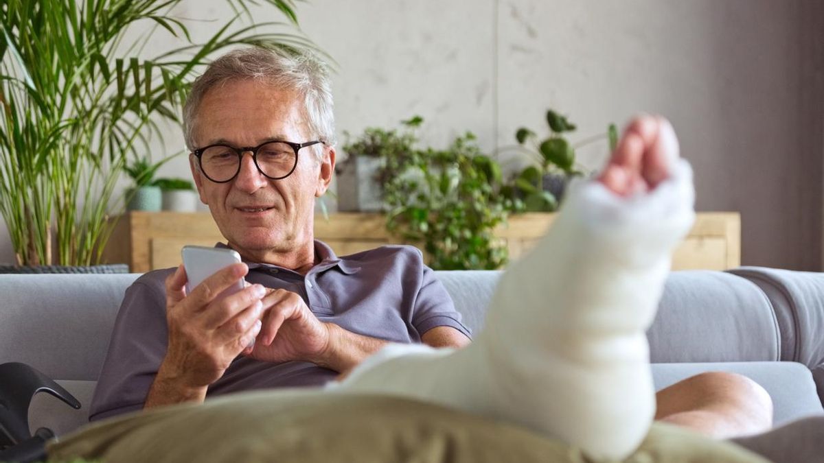 Hombre mayor con una pierna rota en casa