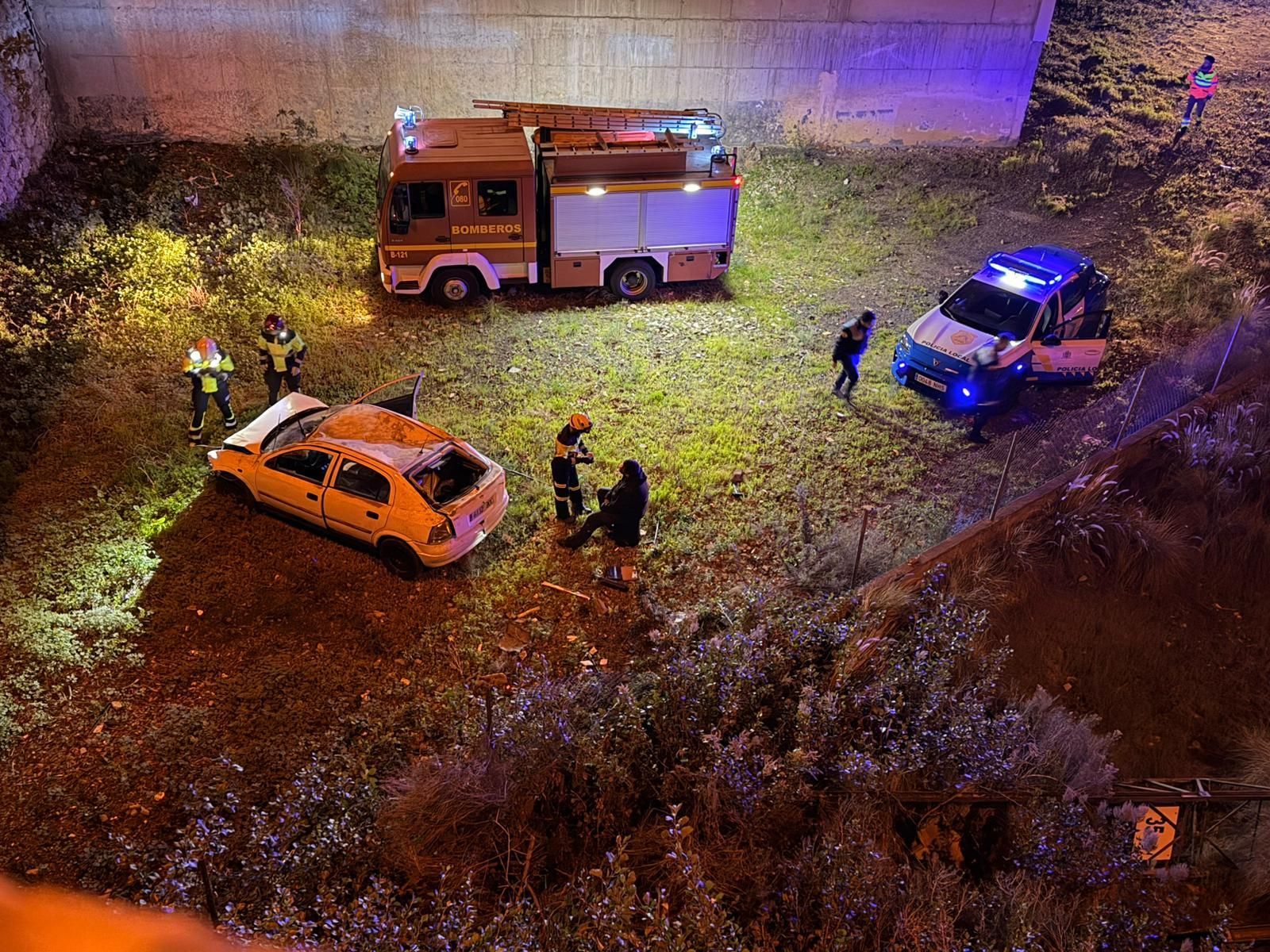 Bomberos La Palma y Policía Local de Los Llanos de Aridane junto  al coche que ha caído a un solar desde una altura de  unos 10 metros.
