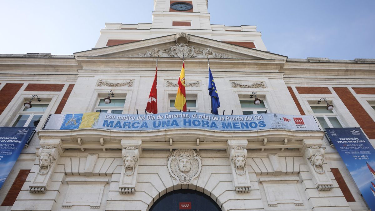 Fachada con la lona alusiva al cambio de hora en el reloj de la Puerta del Sol.