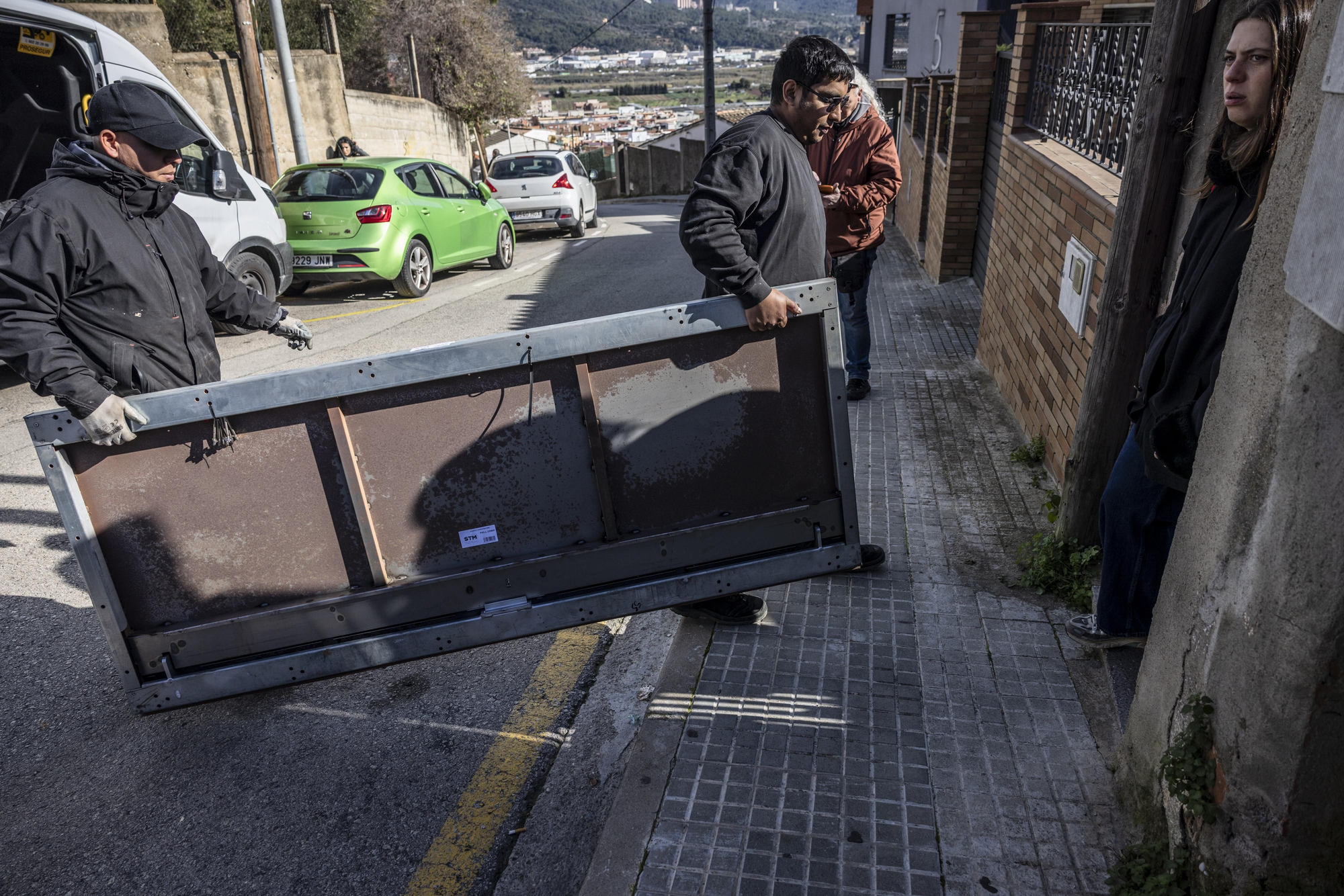 Operarios cargan la puerta metálica para tapiar el acceso al apartamento de Abdul y Zohran tras ser desahuciados