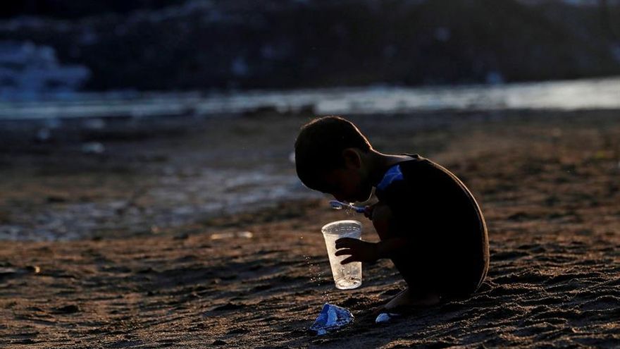 Un niño hondureño se cepilla los dientes este martes, en la orilla del río Suchíate tras que la Guardia Nacional de México impidiera a migrantes cruzar, en Tecún Umán (Guatemala)