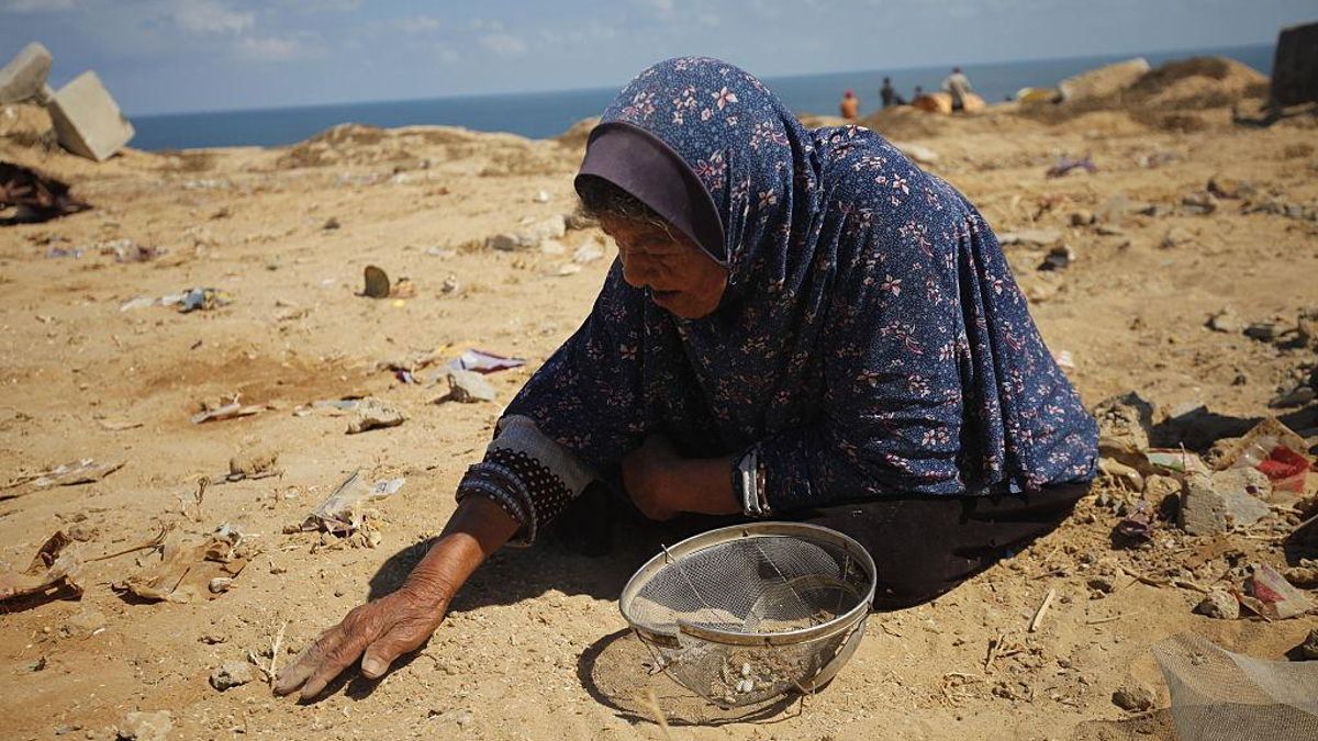 Una mujer palestina trata de recuperar del suelo granos de arroz, judías de los paquetes de ayuda lanzados desde el aire