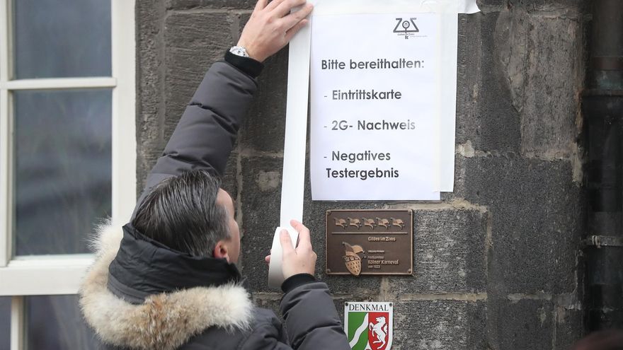 Un empleado de un bar de Colonia coloca un cartel con las normas anti covid a seguir en el local, en vísperas del carnaval alemán y ante el aumento de contagios en el país