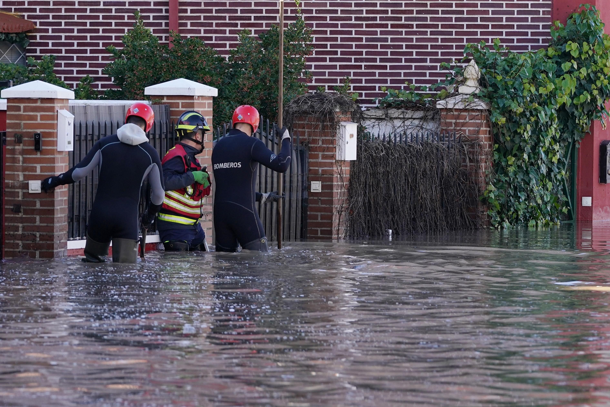 Efectivos de bomberos conversan con una afectada por las inundaciones del río Cega en la localidad vallisoletana de Viana de Cega que se ha quedado atrapada en su vivienda.