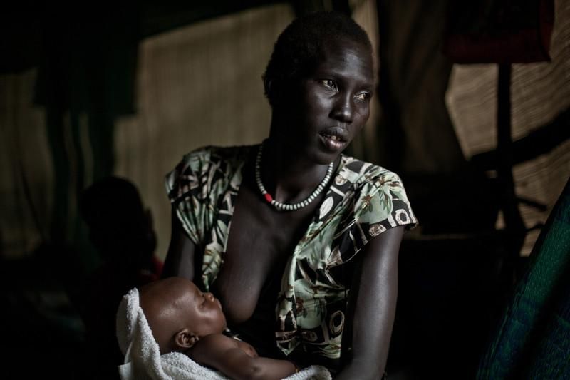 Mari Abrey dio a luz a un bebé en marzo de 2014 en Mingkaman. Cuenta las duras condiciones en las que tuvo el bebé dentro de la tienda y cómo llegó hasta allí. Tiene dos hijos más y alerta con su mirada la imposibilidad de alimentarlo  Ella es una de las casi 100.000 personas que viven en Mingkaman, el mayor campo de desplazados de Sudán del Sur. Aquí se instalan las personas que huyen de la violencia desde que empezó el conflicto en el país africano en diciembre de 2013. El campo de desplazados de Mingkaman, en Awerial, se ha convertido en refugio para casi 100.000 personas, principalmente de la etnia dinka, que huyeron de los enfrentamientos violentos en el estado de Jonglei, principalmente de la ciudad de Bor. Las personas que llegan necesitan agua, comida y un techo dónde refugiarse. Sudán del Sur afronta una grave crisis a causa de la violencia que se desató en diciembre de 2013 entre las fuerzas leales al presidente Salva Kiir, y los combatientes aliados al ex vicepresidente Riek Machar. Cerca de un millón de personas han tenido que abandonar sus hogares a causa de los enfrentamientos y se han quedado sin medios propios para alimentarse. Un tercio de la población sufre inseguridad alimentaria./Pablo Tosco/Oxfam Intermón