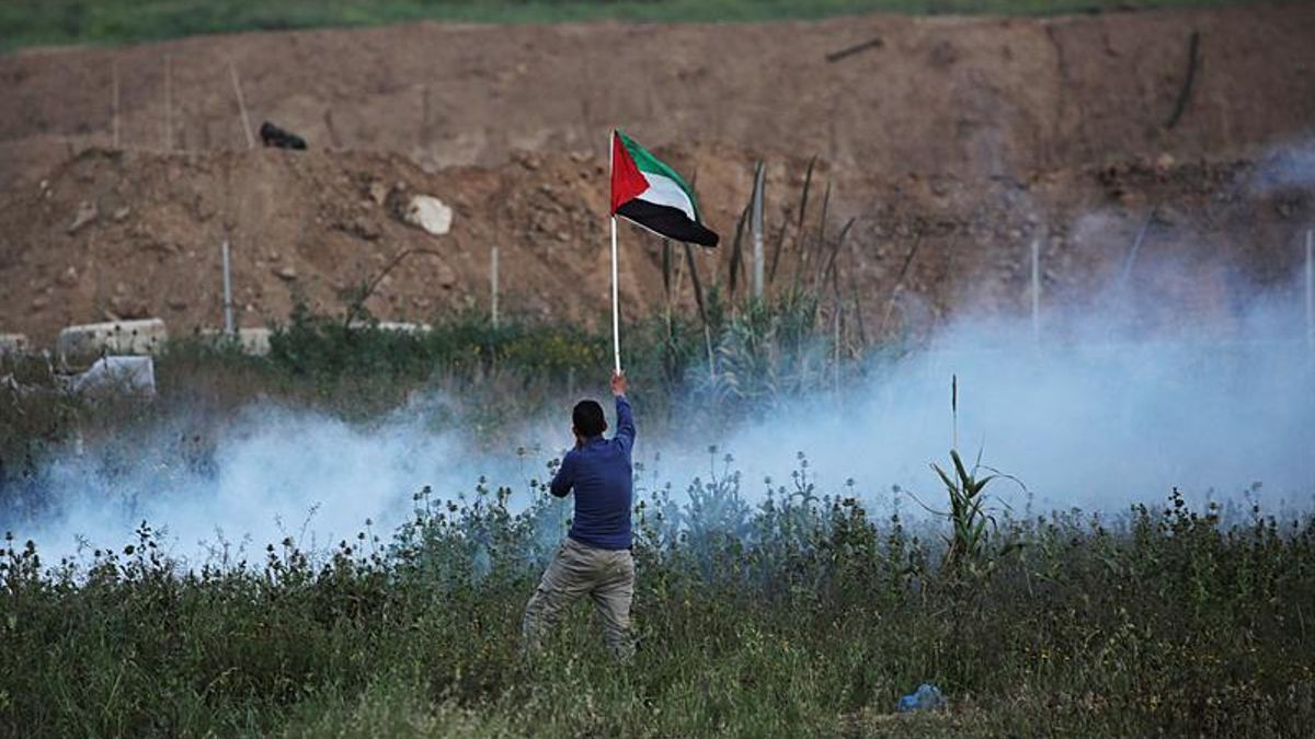 Un hombre ondea una bandera palestina durante enfrentamientos con tropas israelíes a lo largo de la frontera entre Israel y la Franja de Gaza.