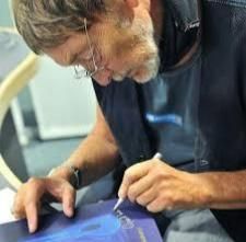 Chris Rea firmando con su mano izquierda.