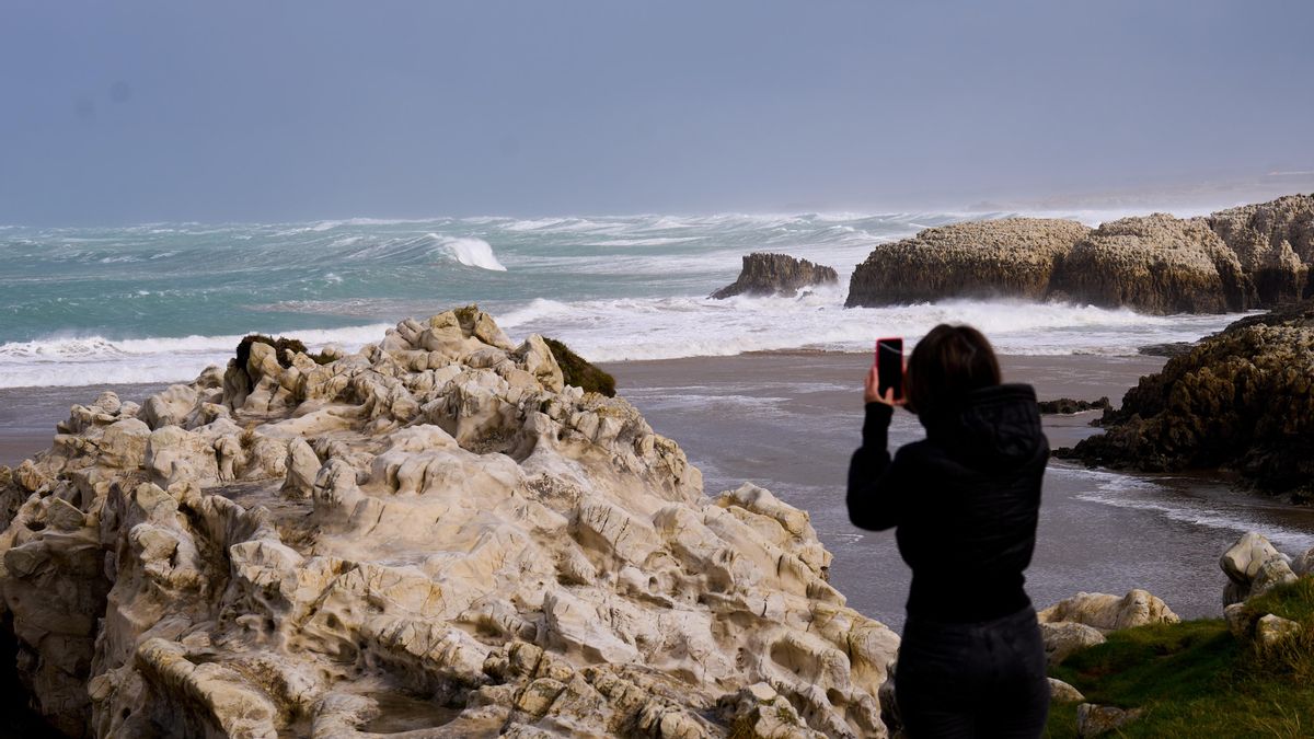 Una persona fotografía las olas rompiendo en Santander. ARCHIVO