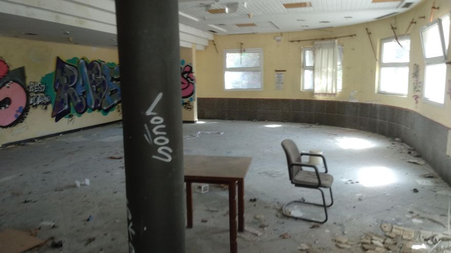 El interior de otro de los edificios, prácticamente sin muebles y lleno de suciedad. Solo conserva una mesa y una silla.