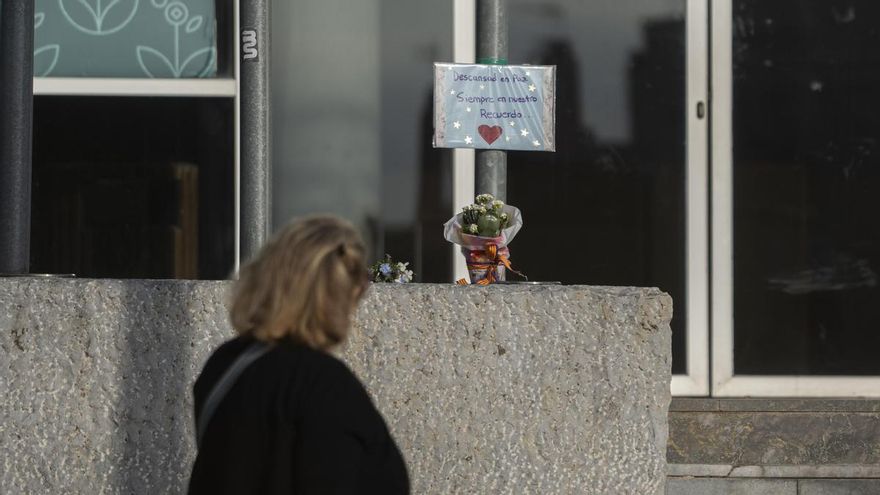 Una mujer observa un cartel y un ramo de flores en honor de los fallecidos por la DANA en el exterior de la morgue de Feria Valencia.