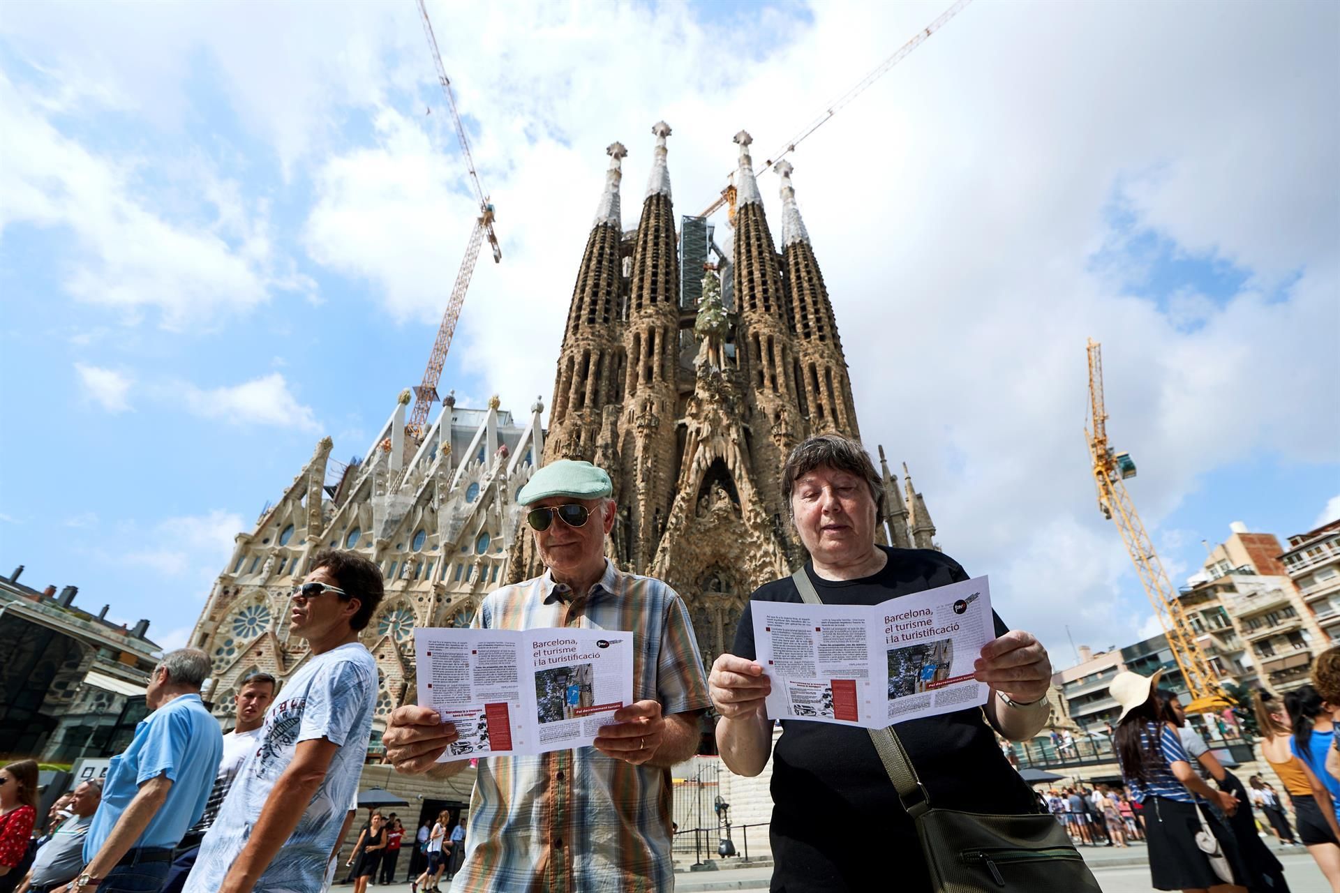 Vecinos reparten folletos contra la masificación turística frente a la Sagrada Família, en 2019