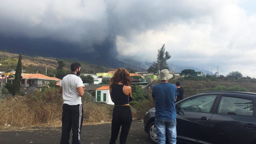 Varios vecinos desalojados contemplan en un barrio de El Paso el volcán bajo una gran nube de ceniza.