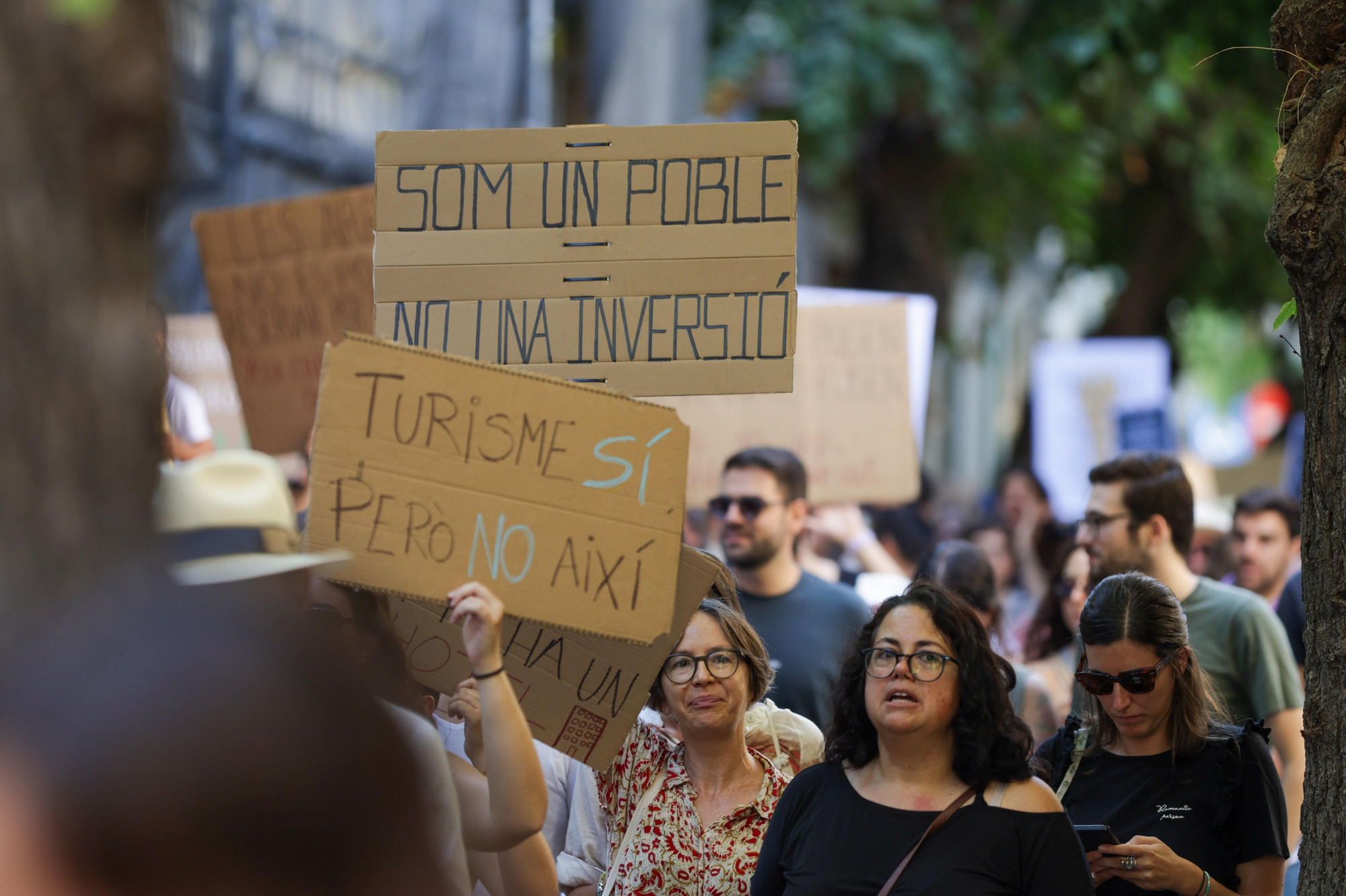 Carteles que rezan: "Somos un pueblo, no una inversión" y "Turismo sí, pero no así"