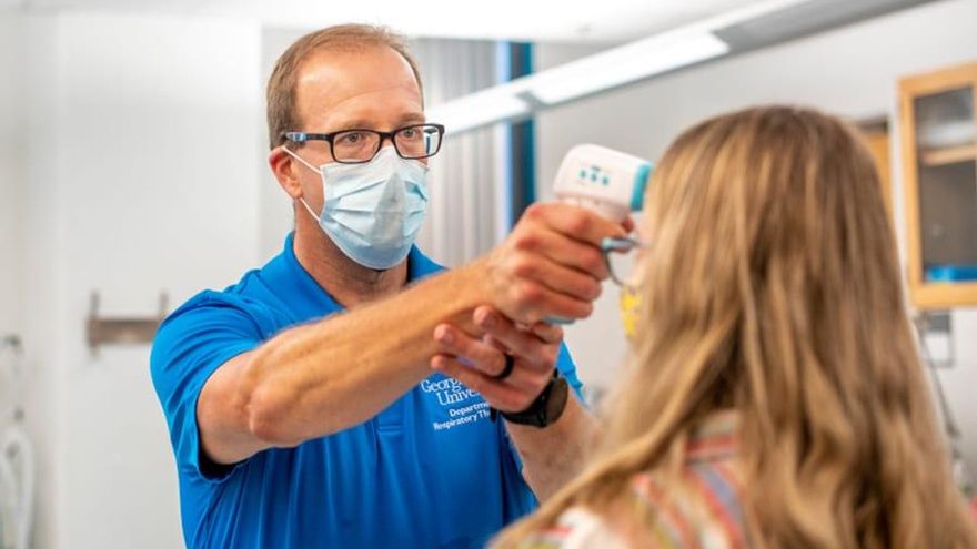 Brent Murray, profesor de la universidad, toma la temperatura de una alumna antes de entrar al laboratorio.