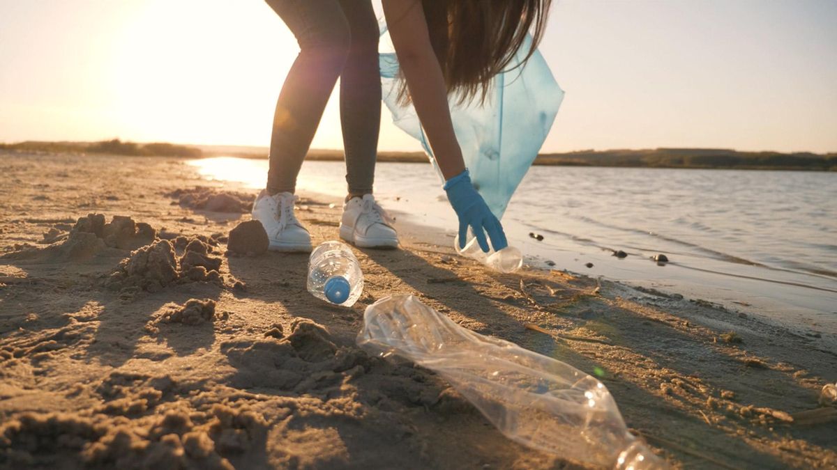 Una mujer recogiendo residuos de la playa.
