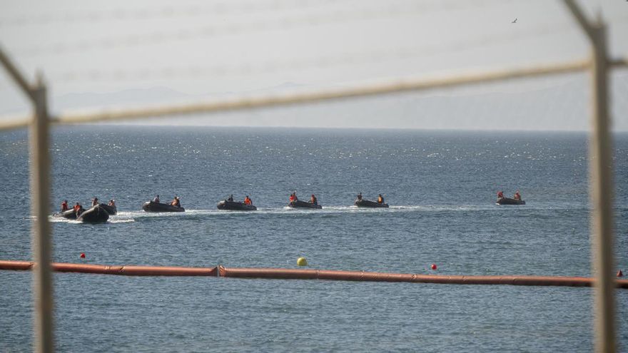 Operarios instalando la barrera flotante en El Tarajal (Ceuta).