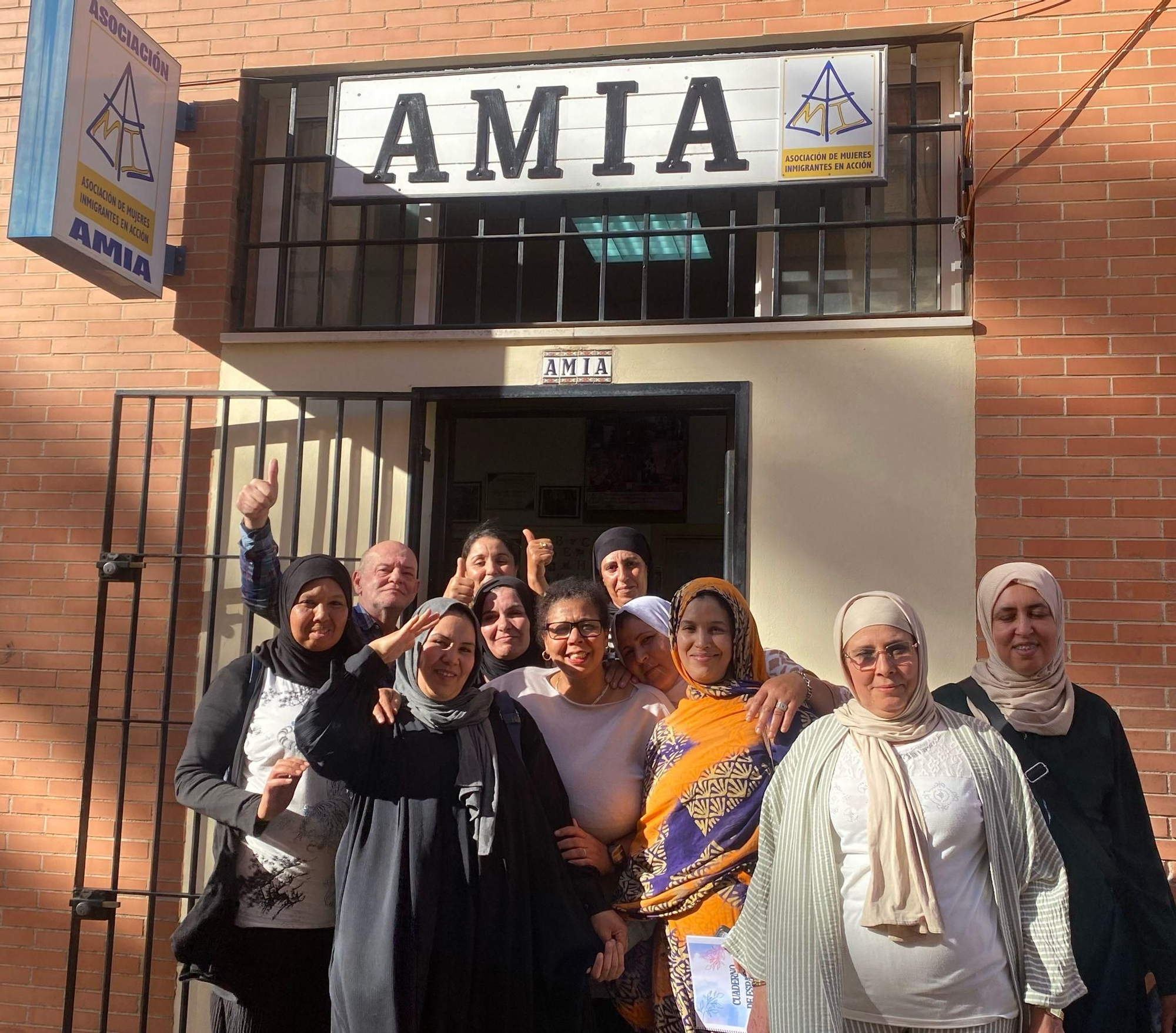 La presidenta de AMIA, en la puerta de su sede, rodeada de socias, usuarias y colaboradores de la asociación.