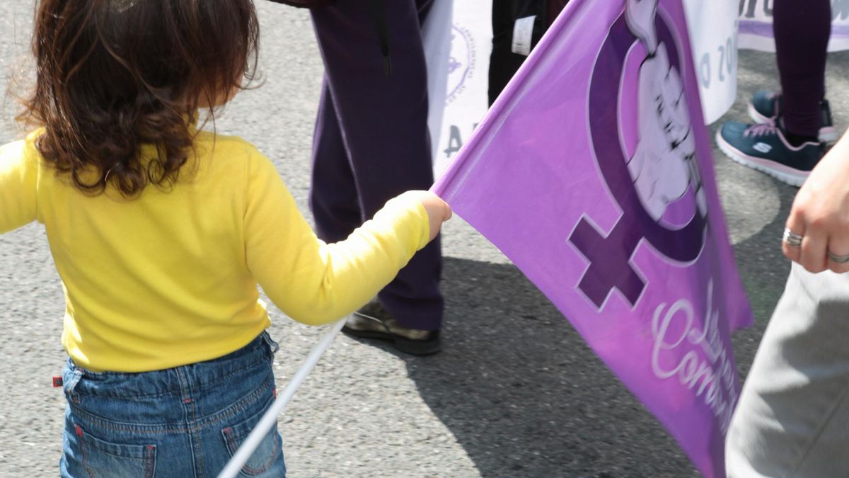 Una menor acompañada por su familia durante la marcha del 8M, en Sevilla.