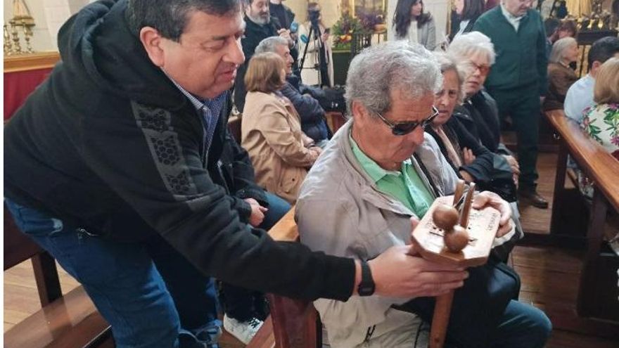 Una persona con discapacidad visual conoce, mediante el tacto, uno de los instrumentos tradicionales de la Semana Santa toledana, la carraca