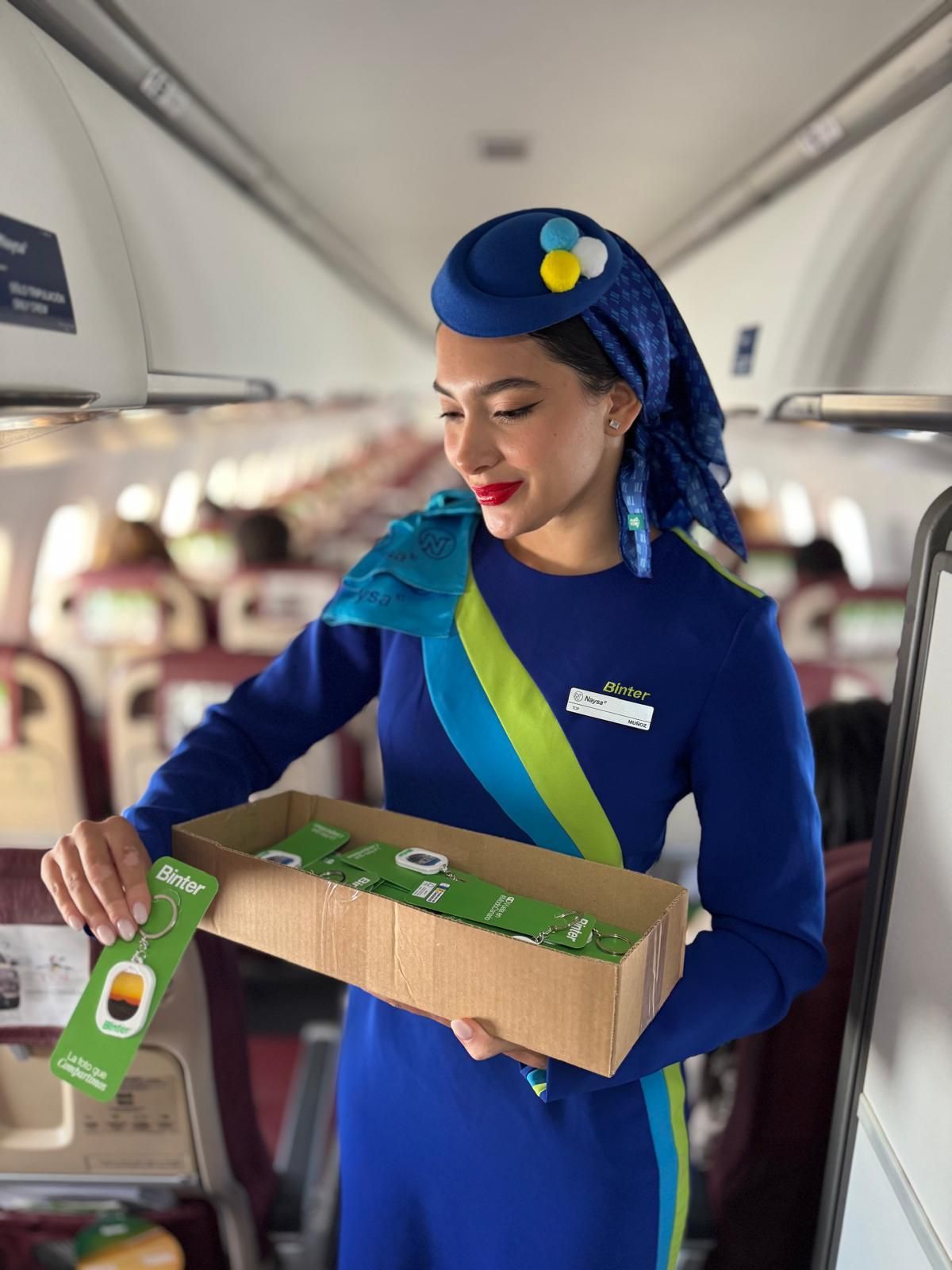 Una azafata de Binter reparte llaveros en una vuelo.