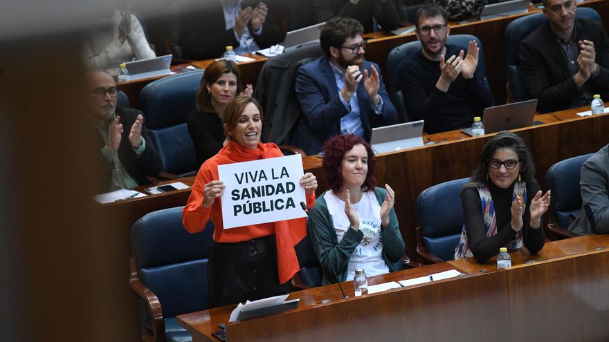 Mónica García enseña un cartel con un "Viva la sanidad pública' en el pleno de la Asamblea.