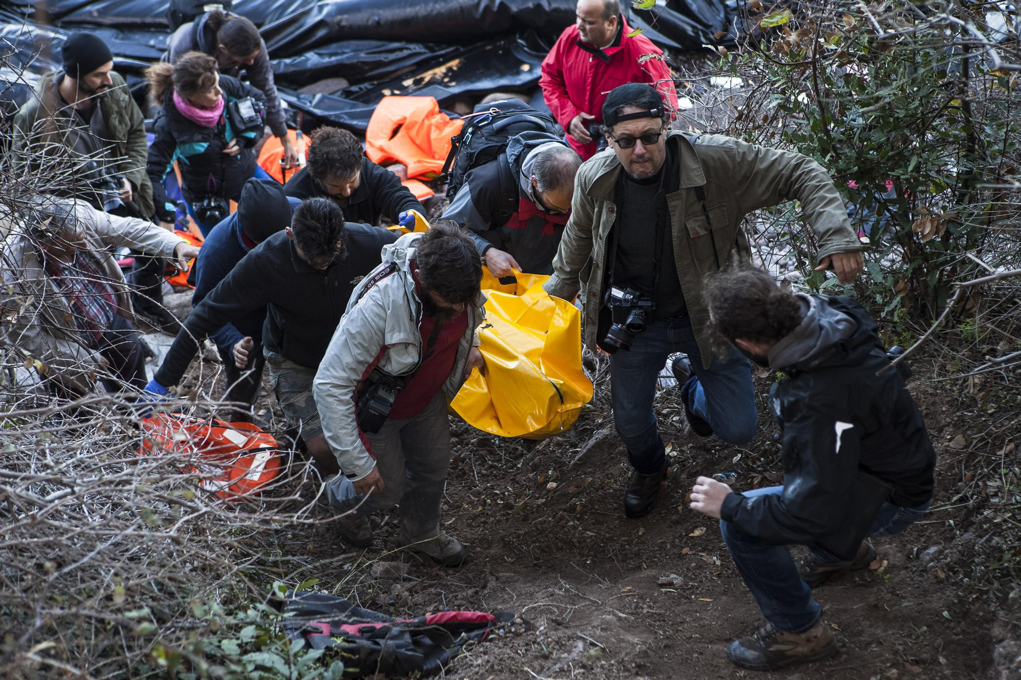 Un grupo de fotógrafos trasladan el cadáver de un refugiado en una playa del norte de Lesbos, Grecia