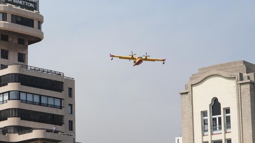 Un hidroavión destinado a las labores de extinción del incendio forestal que afecta a la isla de Tenerife sobrevuela la capital de la isla durante una operación de recarga de agua
