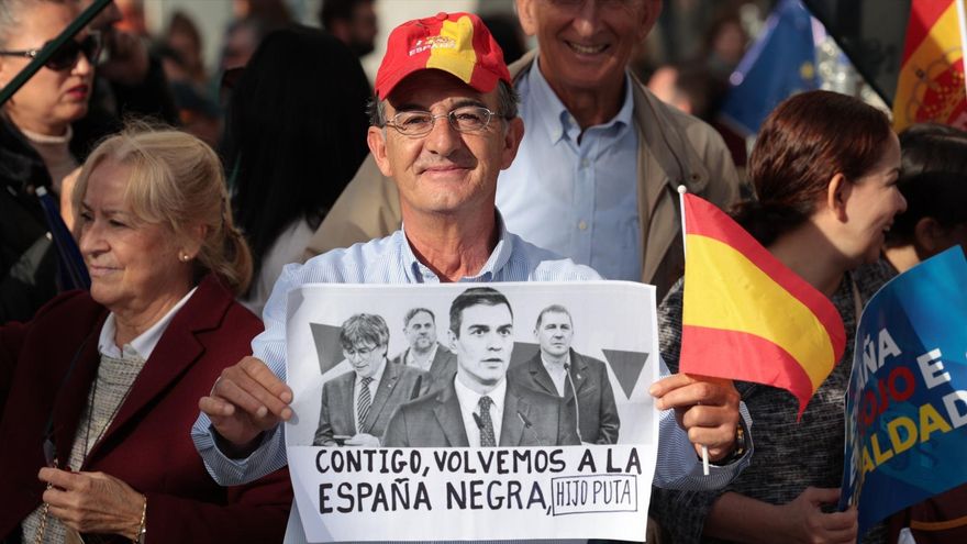 Un manifestante sujeta una pancarta del presidente del Gobierno en funciones durante una concentración contra la amnistía, en la Puerta del Sol, Madrid.