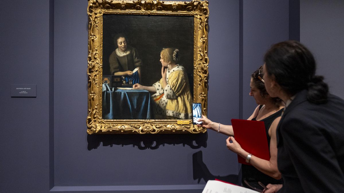 Personas observan el cuadro "La amante y la criada" de Vermeer 