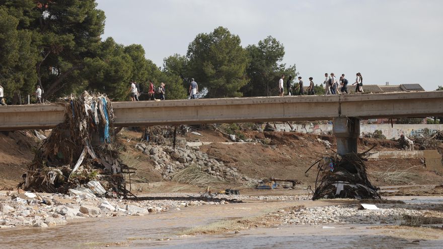 Varias personas cruzan por un puente sobre el barranco del Poyo de Paiporta, Valencia.