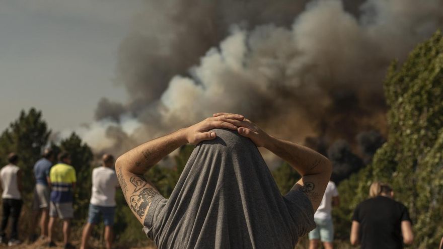 Un hombre observa la columna de humo del incendio forestal que permanece activo en Verín (Ourense), cerca de unas viviendas.
