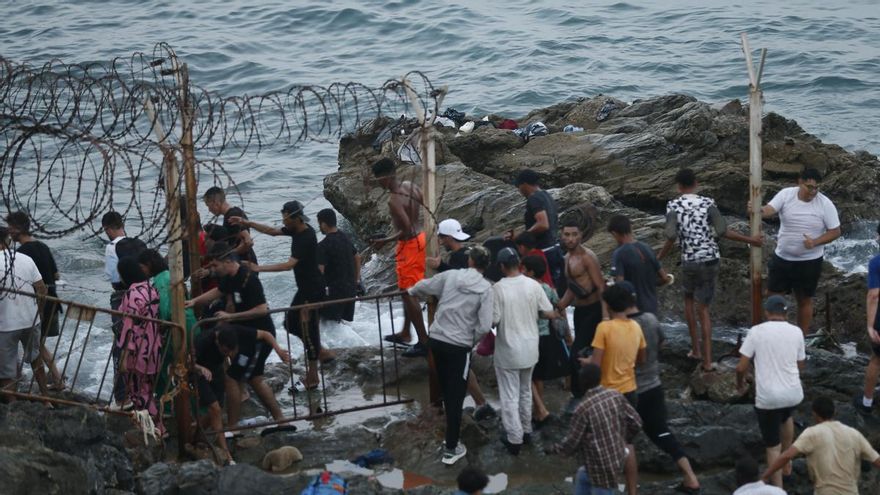 Imagen de personas escapando este jueves de las fuerzas antidisturbios marroquies que han desalojado a las masas que se encontraban cerca de la frontera con Ceuta. EFE / Mohamed Siali.