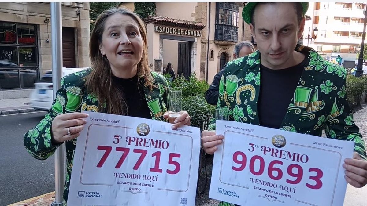 Rosa y Julio Acebal Muñiz, propietarios de la administración 'El Estanco de la Suerte', en Oviedo, con los carteles de los dos números premiados 
del sorteo de la lotería de Navidad 2025.