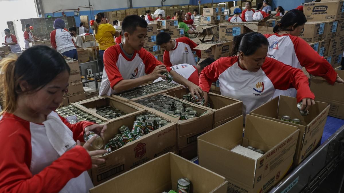 Voluntarios y trabajadores del gobierno local trabajan juntos para juntar comida y bebida para los evacuados al centro de Metro Manila, este domingo