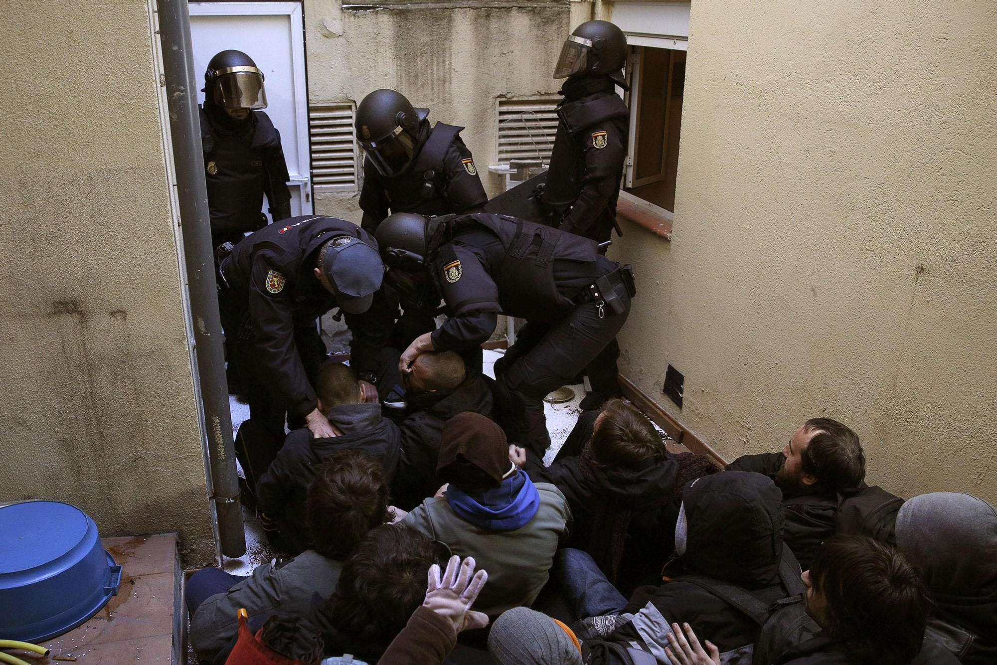 Varios policías antidisturbios levantando de forma violenta a los activistas antidesahucios