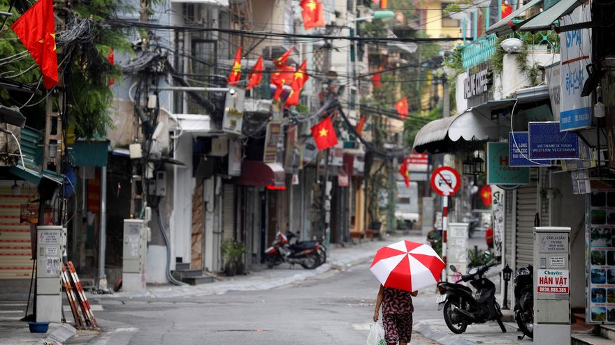 Una mujer camina bajo banderas nacionales vietnamitas en la calle en Hanoi, Vietnam. EFE/EPA/LUONG THAI LINH/ Archivo