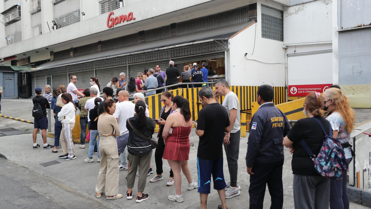 Personas hacen fila en un supermercado para abastecerse este sábado en Caracas (Venezuela).