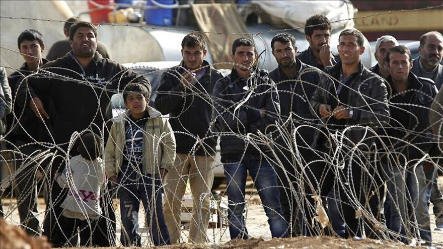 Refugiados sirios esperan para cruzar la frontera y pasar a Turquía cerca de Kobane (Siria).