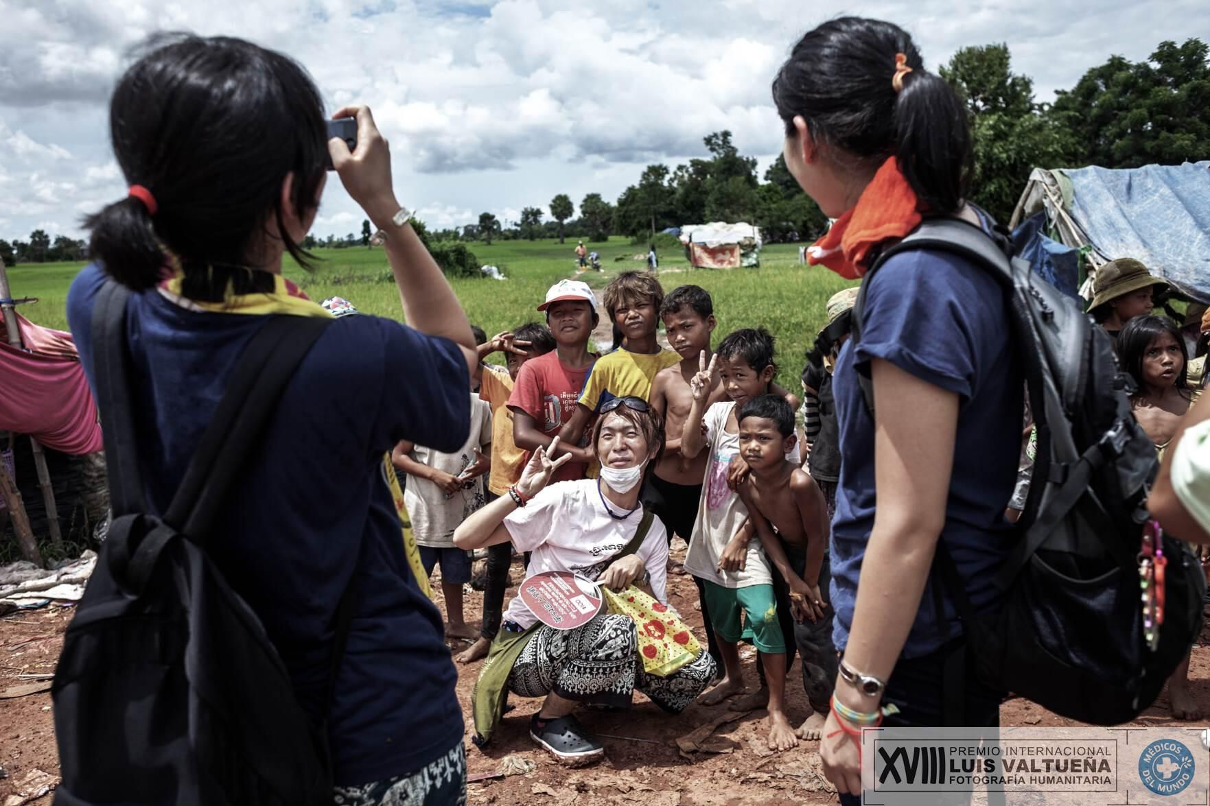 El segundo finalista es David Rengel, con la serie titulada “Turismo sucio”, que muestra a un grupo de turistas japoneses durante una visita guiada a un vertedero de Camboya. Imagen: Un turista japonés se fotografía con los niños que trabajan en el basurero. Los turistas dan caramelos y hacen fotos a los niños. Existe una ruta turistica en la ciudad que tiene el vertedero como un lugar de atracción turística./ Fotografía: David Rengel