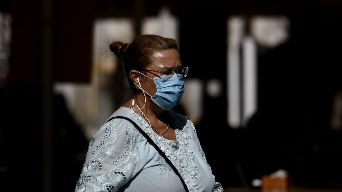 Una mujer camina con mascarilla