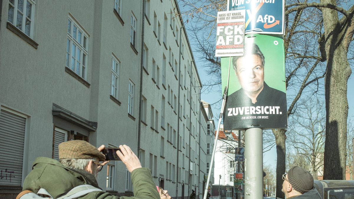 Jochen hace una foto a la pancarta 'fck AfD', sostenida por Ilon, sobre el cartel de la candidata ultraderechista en Lichtenberg.