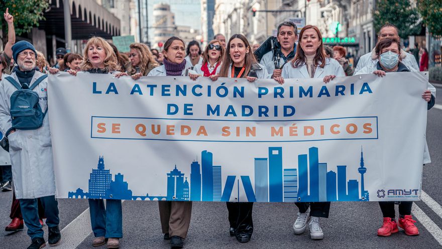 Varias personas caminan llevando una pancarta que reza 'La atención primaria de Madrid se queda sin médicos' durante una manifestación de médicos y pediatras.