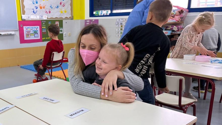 Una mestra abraça a una xiqueta procedent del conflicte d'Ucraïna en el CEIP Nuestra Señora del Rosario de Torrevella.