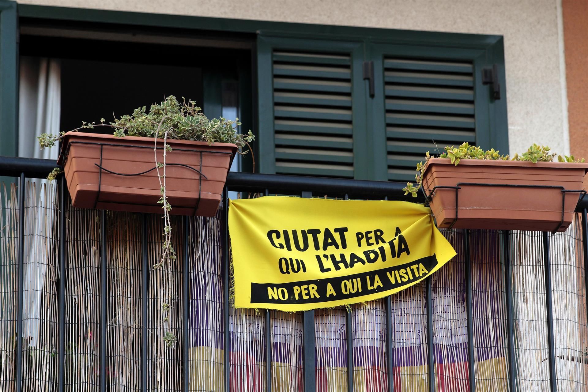 Una pancarta con el lema "Ciudad para quien la habita, no para quien la visita" colgada de un balcón del barrio de Santa Catalina, en Palma