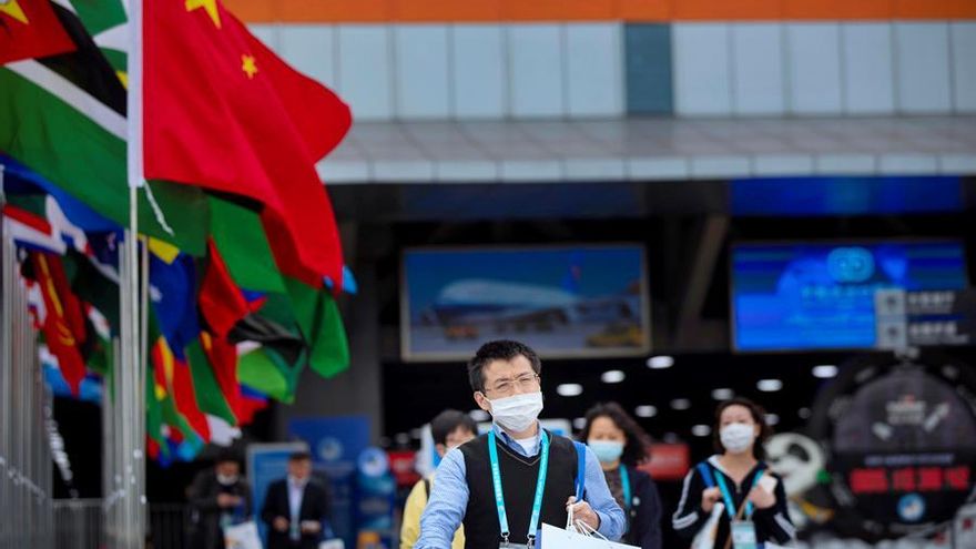 Los visitantes, protegidos con mascarillas, caminan frente a la 3ª Exposición Internacional de Importación de China en Shanghai, China.