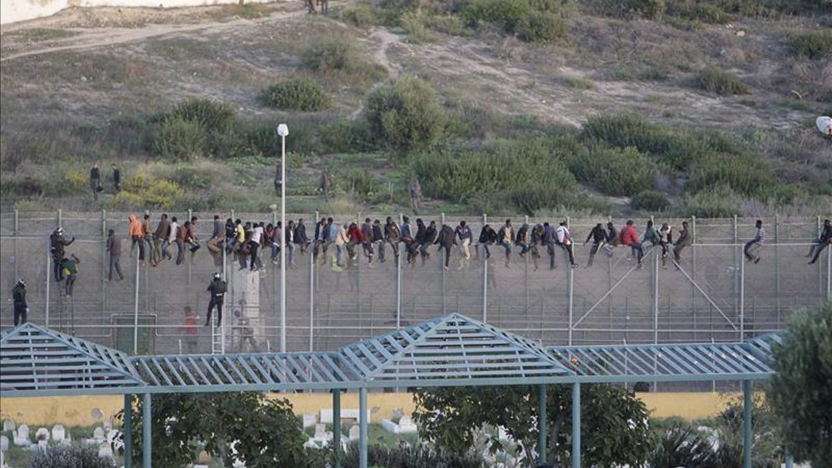 Decenas de personas encaramadas en la valla de Melilla/ Efe