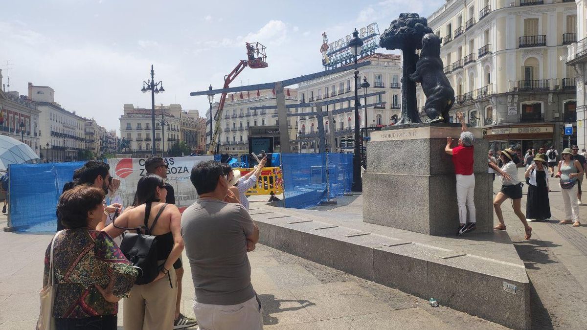 Turistas esperan su turno para fotografiarse tocando la cola al Oso de la Puerta del Sol.